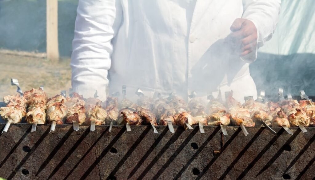 a-chef-cooking-meat-on-skewers-on-the-grill